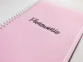 Różowy notatnik z napisem "Planowanie" pomoże Ci ustalić, kogo zaprosić na wesele.