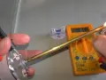 Come controllare un termostato con il tester: un multimetro digitale misura la resistenza di un componente metallico riscaldato.