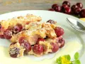 Zwei Portionen Kirschenmichel, ein köstliches Dessert, serviert mit Vanillesauce und bestäubt mit Puderzucker. Ein perfektes Kirschenmichel Rezept.