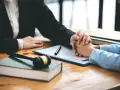 Abogada brinda asesoría laboral para trabajadores. Un mazo de juez y un libro sobre la mesa simbolizan la justicia.