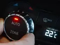 Hand dreht am Regler der **Klimaanlage Auto** auf 22 Grad Celsius. Rote LED leuchtet.