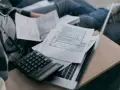 Osoba przegląda dokumenty podatkowe, kalkulator i laptop. Analiza składnik zmienny stawki sieciowej.