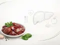 Surowa wątróbka na talerzu, obok czosnek i szpinak. Grafika wątroby i serca sugeruje, czy wątróbka jest zdrowa.