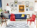 Eklektyczny salon: niebieska kanapa, czerwony fotel, dywan z geometrycznym wzorem, galeria obrazów z motywami natury i sztuki.
