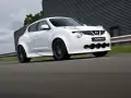 Biały Nissan Juke-R pędzi po torze, jego sportowy wygląd podkreślają szerokie nadkola i agresywny przedni zderzak.