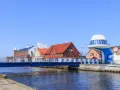 Port rybacki nad Wieprzą z niebieskim mostem i charakterystycznym budynkiem w kształcie statku kosmicznego.