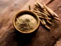 Ashwagandha Pulver in einer Schale und Wurzeln daneben. Wann einnehmen? Ideal morgens oder abends für Stressabbau.