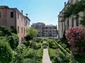 Giardini segreti a Venezia, con un canale e palazzi storici sullo sfondo. Un'oasi di pace tra il verde e i fiori.