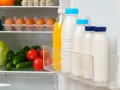 Bouteilles de lait et jus pour une bonne conservation lait frigo. Légumes frais sur l'étagère du bas.
