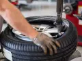 Un meccanico lavora su una gomma. La domanda su ogni quanti km si cambiano le gomme è importante per la sicurezza.