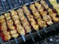 Aromatyczny kebab z kurczaka na rozżarzonych węglach. Soczyste kawałki mięsa pieką się na szpikulcach, tworząc apetyczny widok.