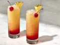 Dwa drinki z Malibu z sokiem ananasowym, lodem, wiśnią i plasterkiem ananasa. Idealne na upalne dni.