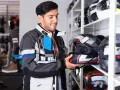 Uomo in negozio di moto esamina un casco, cercando la taglia XS. Corrisponde a una misura piccola, ideale per teste più minute.