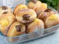 Bomboloni ricetta originale ripieni di crema e cioccolato, cosparsi di zucchero. Un dolce invitante pronto da gustare.