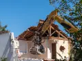 Kruszarka koparki niszczy budynek, realizując pozwolenie na rozbiórkę budynku w granicy działki.