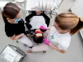 Dwie asystentki stomatologiczne pracują przy pacjencie. Zastanawiasz się, ile zarabia asystentka stomatologiczna?