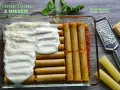 Cannelloni z mięsem mielonym i sosem beszamelowym w naczyniu żaroodpornym, gotowe do pieczenia. Obok tarka i kawałek parmezanu.