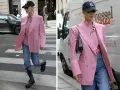Kobieta w marynarce w odcieniu **magenta kolor** i jeansach idzie ulicą. Czapka z daszkiem i okulary dodają jej miejskiego stylu.