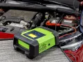 Carrozzeria rossa con cofano aperto, motore e batteria. Un caricabatterie verde è collegato alla batteria, suggerendo una batteria della macchina scarica.