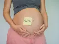 Brzuch kobiety w ciąży z karteczką "40+". To dowód, że ciąża po 40. jest możliwa i piękna.