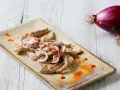 Straccetti di vitello conditi con cipolla rossa e un filo d'olio piccante, pronti per essere gustati.