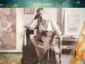 Hilma af Klint barn, en ung kvinna i en vit blus och mörk kjol, sitter vid ett bord omgiven av sina abstrakta målningar.