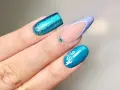 Unghie con glitter blu elettrico, french manicure con glitter azzurro e decorazioni floreali bianche. Nuove forme unghie che ispirano.