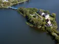 Ełk: zamek krzyżacki na wyspie, idealne miejsce na zwiedzanie. Most prowadzi do historycznych budynków otoczonych zielenią i wodą.