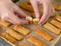 Ręce rozdzielają chrupiące paluszki rybne. Idealne na szybki obiad, warto sprawdzić paluszki rybne kcal.