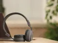 Szare słuchawki dynamiczne na drewnianym blacie, obok laptopa. Idealne do słuchania muzyki i podcastów.