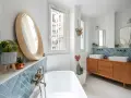 Élégante salle de bain moderne avec baignoire, double vasque sur meuble vintage et carrelage bleu en chevrons.