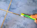 Main tenant utilise une brosse à dents pour nettoyer joint carrelage.