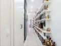 Pasillos estrechos y modernos con estanterías blancas repletas de libros y objetos decorativos, creando un ambiente acogedor.