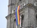 Regenbogenflagge hängt an einer Kirche. Die Bedeutung der Regenbogenflagge steht für Vielfalt und Akzeptanz.