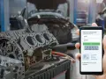 Mechanic uses phone to diagnose P2509 code, likely for a Cummins engine, with a disassembled engine block in the foreground.