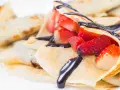 Deliziose crepes senza burro, ripiene di fragole fresche e ricoperte da una golosa salsa al cioccolato.