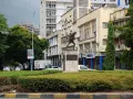 Pomnik żołnierza na tle budynków w Dar es Salaam. W tle widać ruch uliczny i drzewa.