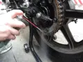 Mano spruzza lubrificante sulla catena della moto. Per sapere ogni quanto ingrassare catena moto, controlla il manuale.