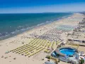 Słoneczna plaża w Rimini, pełna leżaków i parasoli, zaprasza na wakacje. Idealne miejsce na loty do Rimini!