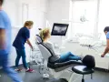 Pacjentka na fotelu dentystycznym, gdzie można wykonać leczenie kanałowe NFZ. Personel przygotowuje narzędzia.