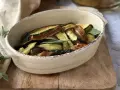 Zucchine in carpione dorate e saporite, guarnite con foglie di salvia fresca, servite in una ciotola rustica.