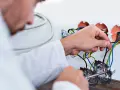 Elektryk dokonuje wymiany instalacji elektrycznej, podłączając przewody do puszek.
