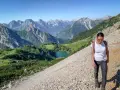 Una donna fa una camminata outdoor in montagna, godendosi il panorama di un lago alpino e vette maestose. Il vero significato di camminata outdoor è qui.