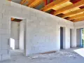 Wnętrze domu w budowie z białych bloczków suporex. Widoczne otwory drzwiowe i drewniany strop. Zapytaj o cenę za metr murowania suporex.