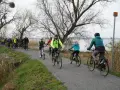 Grupa rowerzystów przemierza malownicze ścieżki rowerowe Szczecina, ciesząc się aktywnym wypoczynkiem nad wodą.