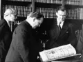Bruno Lohse et d'autres hommes examinant un livre ouvert dans une bibliothèque.