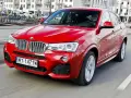 Czerwone BMW X4 w ruchu miejskim. Wady tego modelu mogą dotyczyć widoczności z tyłu i ograniczonej przestrzeni bagażowej.