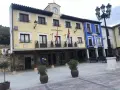 El Ayuntamiento de Tajuña, con su balcón y reloj, preside la plaza. Edificios de colores y farolas completan la escena.