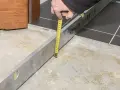 Sprawdzanie, ile schnie wylewka betonowa, za pomocą poziomicy i miarki.