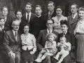 Gros plan sur une famille nombreuse posant pour une photo. On peut y voir des enfants, des adultes et des bébés. Une recherche sur Geneanet pourrait révéler leur nom de famille.